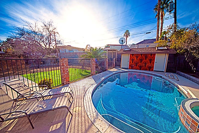 Private backyard pool with lounge chairs and hot tub under a sunny Las Vegas sky